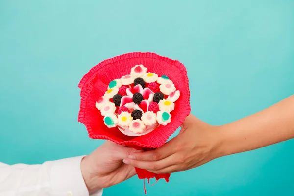 Närbild av mannen ger kvinnan godis gäng blommor. — Stockfoto