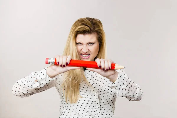 Angry woman holds big pencil in hand — Stock Photo, Image