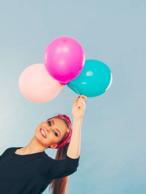 Tatlı gülümseyen kız renkli balonlar tutar.