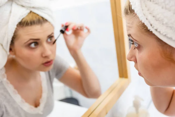Kvinna i badrummet tillämpa mascara på ögonfransarna — Stockfoto