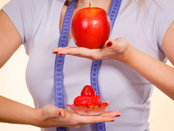 Woman with measuring tape choosing what to eat — Stock Photo, Image