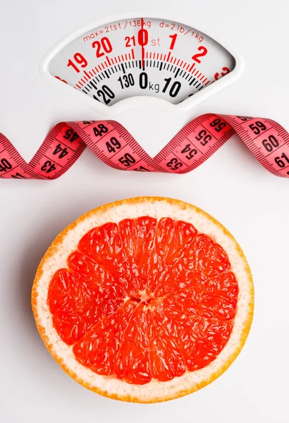 Grapefruit with measuring tape on weight scale. Dieting