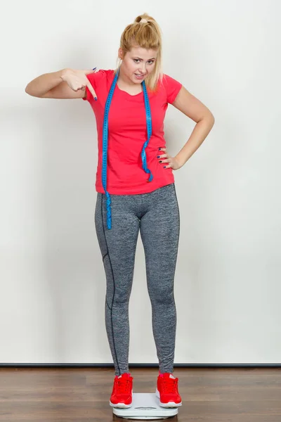 Woman wearing sportswear standing on weight machine — Stock Photo, Image