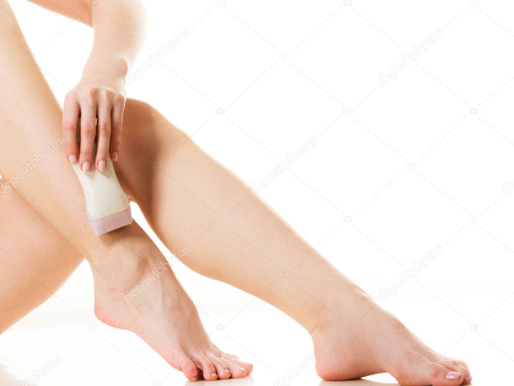 Woman shaving her legs with electric depilator