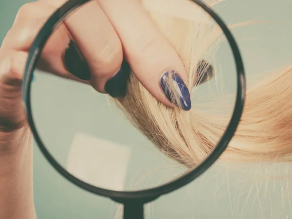 Femme regardant les cheveux à travers la loupe — Photo