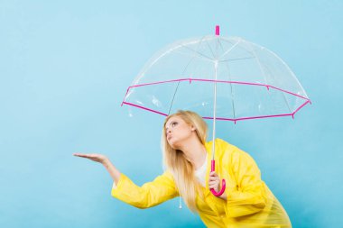 Hava kontrol şemsiye tutan yağmurluk giyen kadın