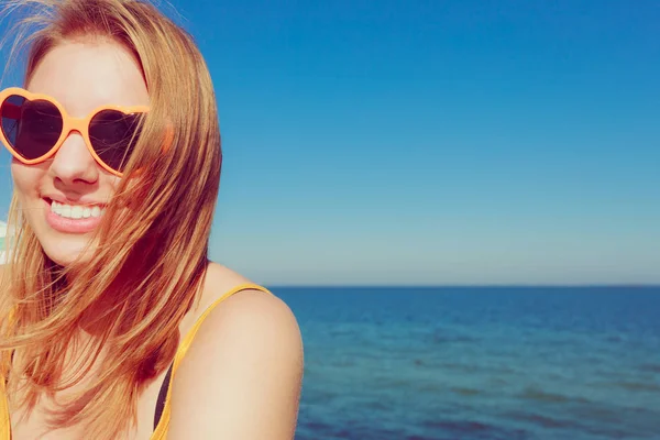 Menina em óculos de sol vermelhos relaxante na costa do mar . — Fotografia de Stock