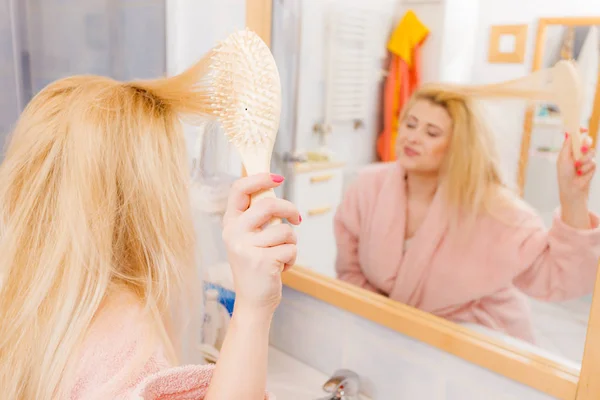 Woman wearing dressing gown brushing her hair