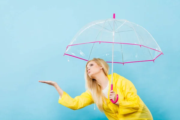 Woman wearing raincoat holding umbrella checking weather