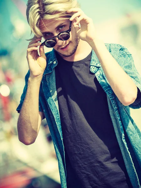 Blonde man standing near harbor in summer