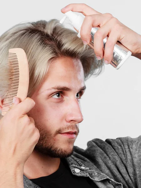 Hombre aplicando spray cosmético a su cabello — Foto de Stock