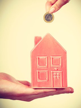 İnsanlar elleriyle küçük ev ve gümüş sikke.