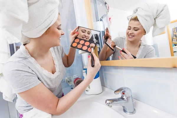 Woman in bathroom applying contour bronzer on brush