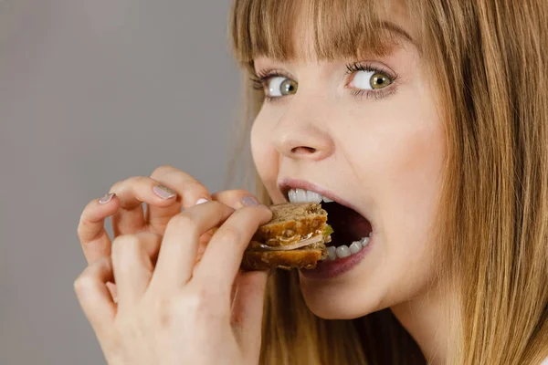 Жінка їсть сендвіч, кусаючи — стокове фото
