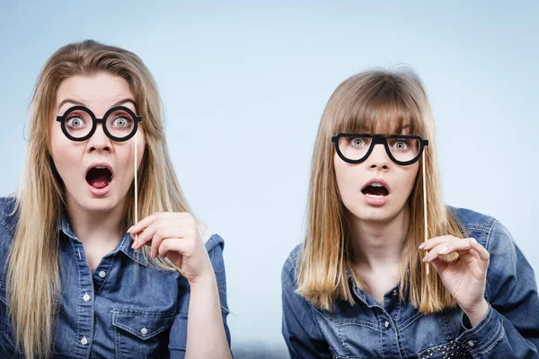 Dos mujeres felices sosteniendo anteojos falsos en palo — Foto de Stock