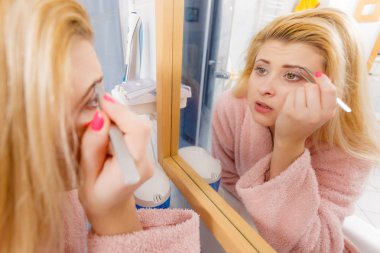 Kaşlarını cımbızla temizleyen kadın.