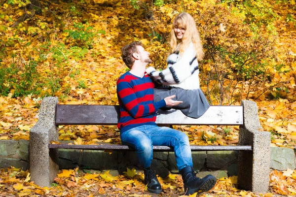 คู่รักในสวนฤดูใบไม้ร่วงบนเก้าอี้ — ภาพถ่ายสต็อก