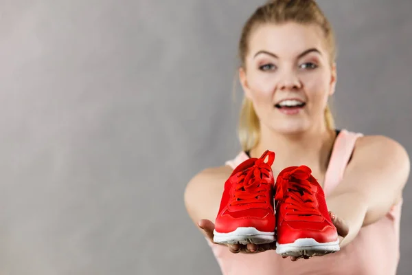 Happy woman presenting sportswear trainers shoes — Stock Photo, Image