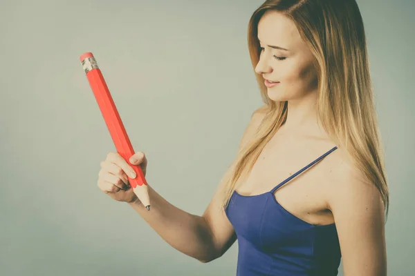 Positive woman holds big pencil in hand — Stock Photo, Image