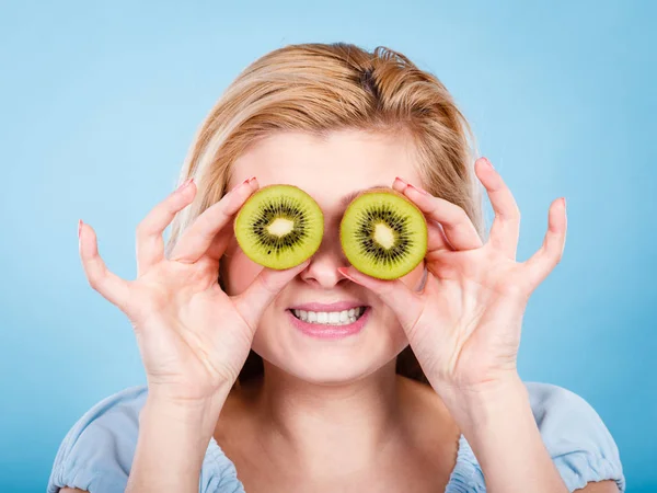 Woman holding green kiwi fruit like eyeglasses — Stock Photo, Image