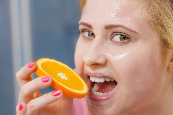 Mulher com máscara de gel no rosto segurando laranja — Fotografia de Stock