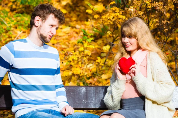 Girl show feelings to man in autumnal park.