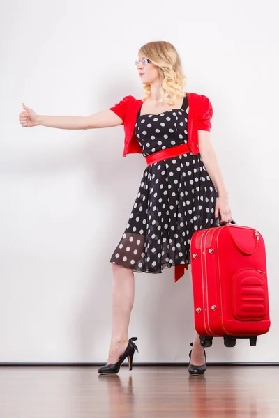 Женщина с красным чемоданом автостопом — стоковое фото