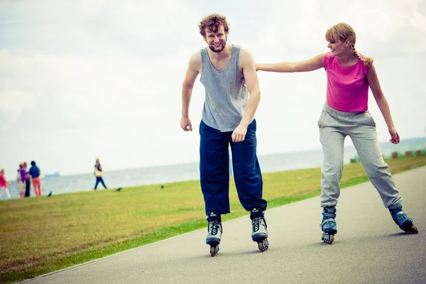 Νεαρό ζευγάρι κρατώντας τα χέρια ενώ rollerblading — Φωτογραφία Αρχείου