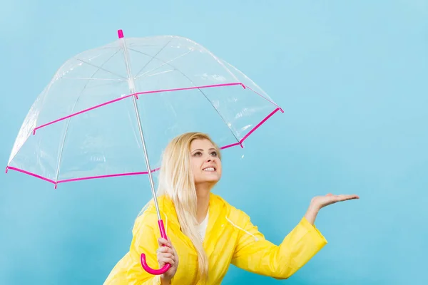 Женщина в плаще, держащая зонтик, проверяет погоду — стоковое фото