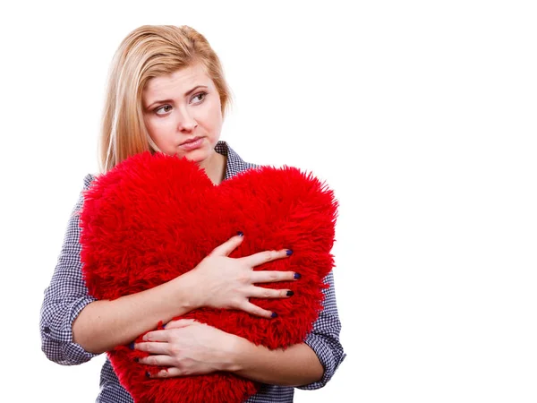 Menina triste segurando grande travesseiro vermelho em forma de coração — Fotografia de Stock