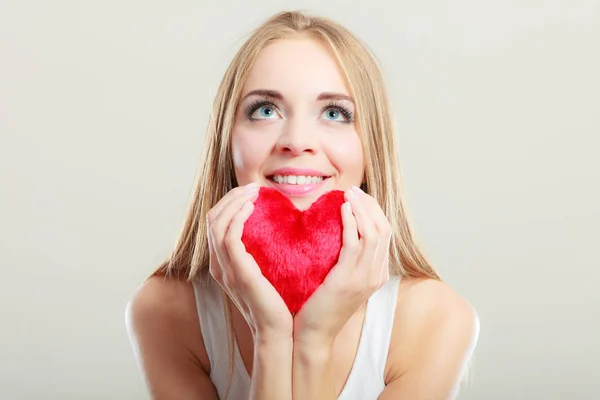 Mujer sonriente sosteniendo el símbolo de amor corazón rojo — Foto de Stock