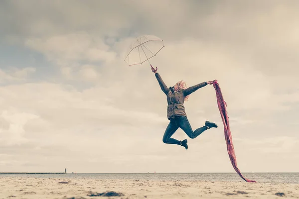 Happy woman jumping with scarf on beach — Stock Photo, Image
