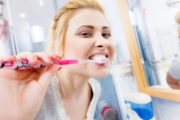 Mulher escovando os dentes de limpeza no banheiro — Fotografia de Stock