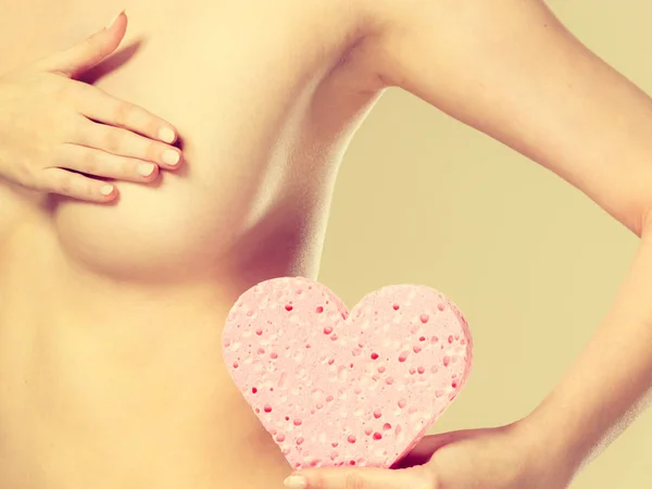 Meztelen nő, karján rózsaszín szív szivacs, kezében. — Stock Fotó
