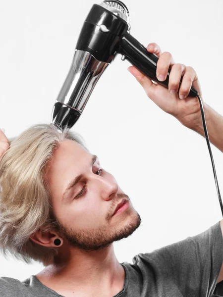 Young man drying hair with hairdryer — Stock Photo, Image