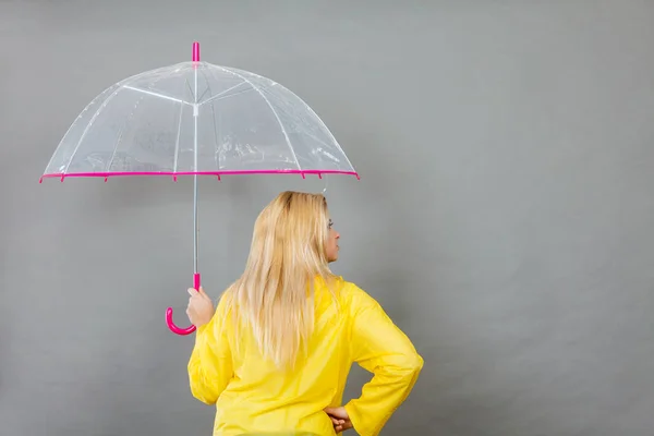 Mujer vistiendo impermeable sosteniendo paraguas comprobando el clima — Foto de Stock