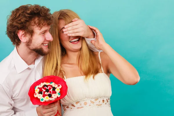 Muž dává žena candy parta pokrývající její oči. — Stock fotografie