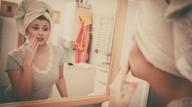 Bir kadın aynadaki yansımasına bakıyor.