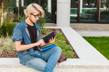 Hipster adam kenarında oturan tablet ile