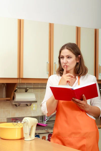 Femme au foyer avec livre de cuisine dans la cuisine . — Photo