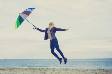 Kadın ile renkli şemsiye plajda atlama
