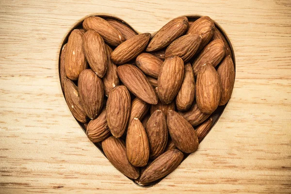 Heart shaped almonds on wooden surface background