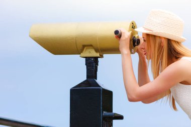 Teleskopla bakarak güneş şapkalı kadın turist