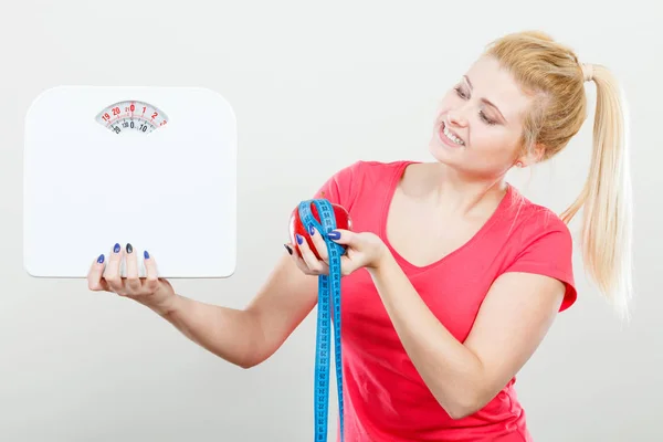 Kvinna som håller apple, tejp och vikt mätmaskin — Stockfoto