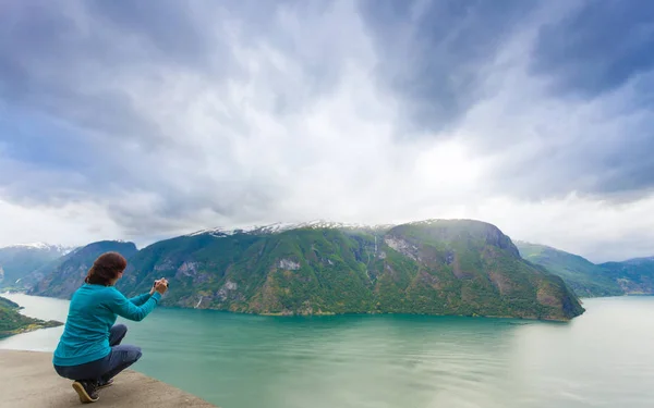 Kvinnlig turist tar foto på norsk fjord — Stockfoto