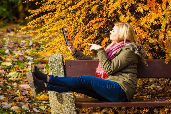 Kobieta, relaksujący siedzący na ławce w parku za pomocą tabletu — Zdjęcie stockowe