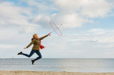 Kadın ile şeffaf şemsiye plajda atlama
