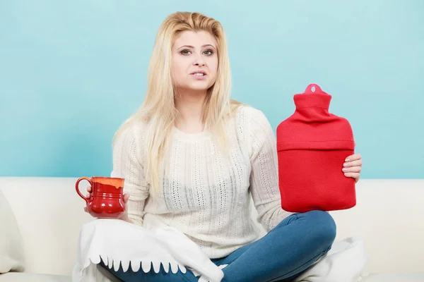 Femme tenant une bouteille d'eau chaude et du thé dans une tasse — Photo