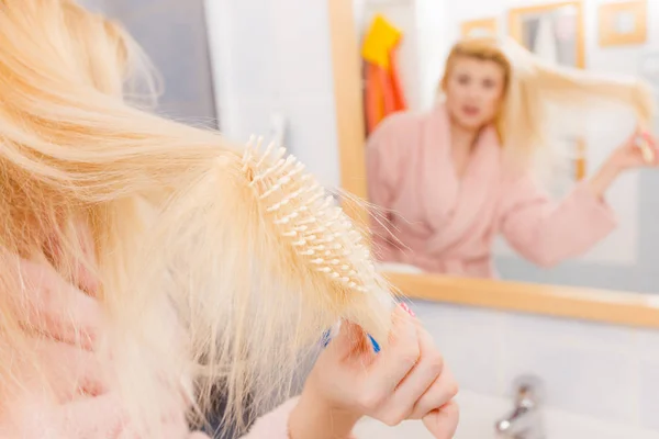 Mujer conmocionada usando bata cepillándose el pelo — Foto de Stock