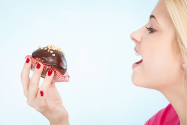 Çikolatalı kek tutan kadın ısırmak üzere.